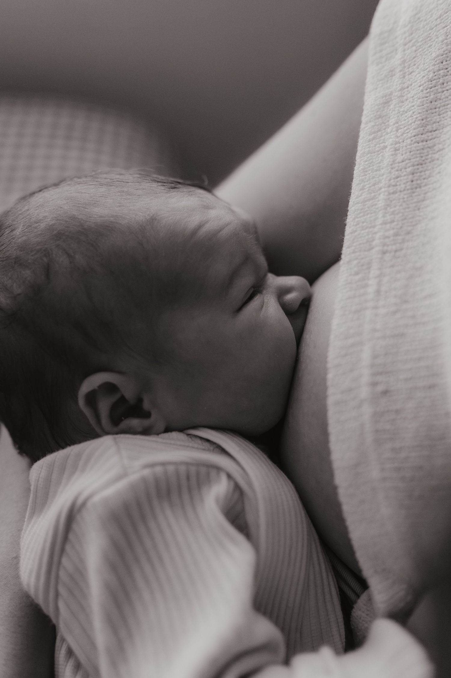 Black and white photo of a newborn baby breastfeeding, peacefully nursing close to mother.