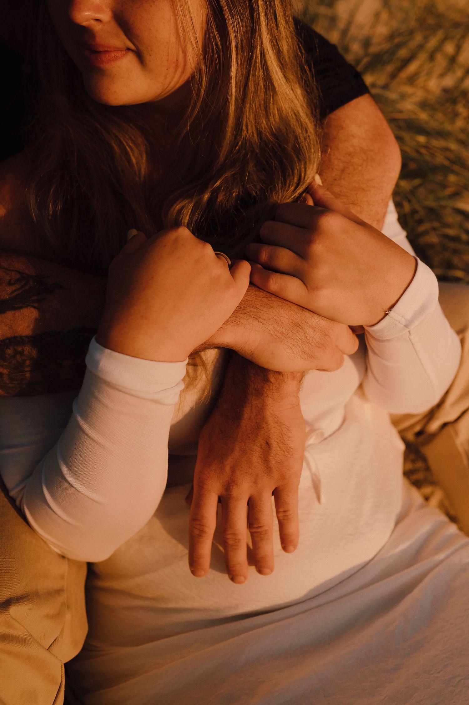 A couple embracing warmly at golden hour, hands intertwined in a tender and romantic moment.