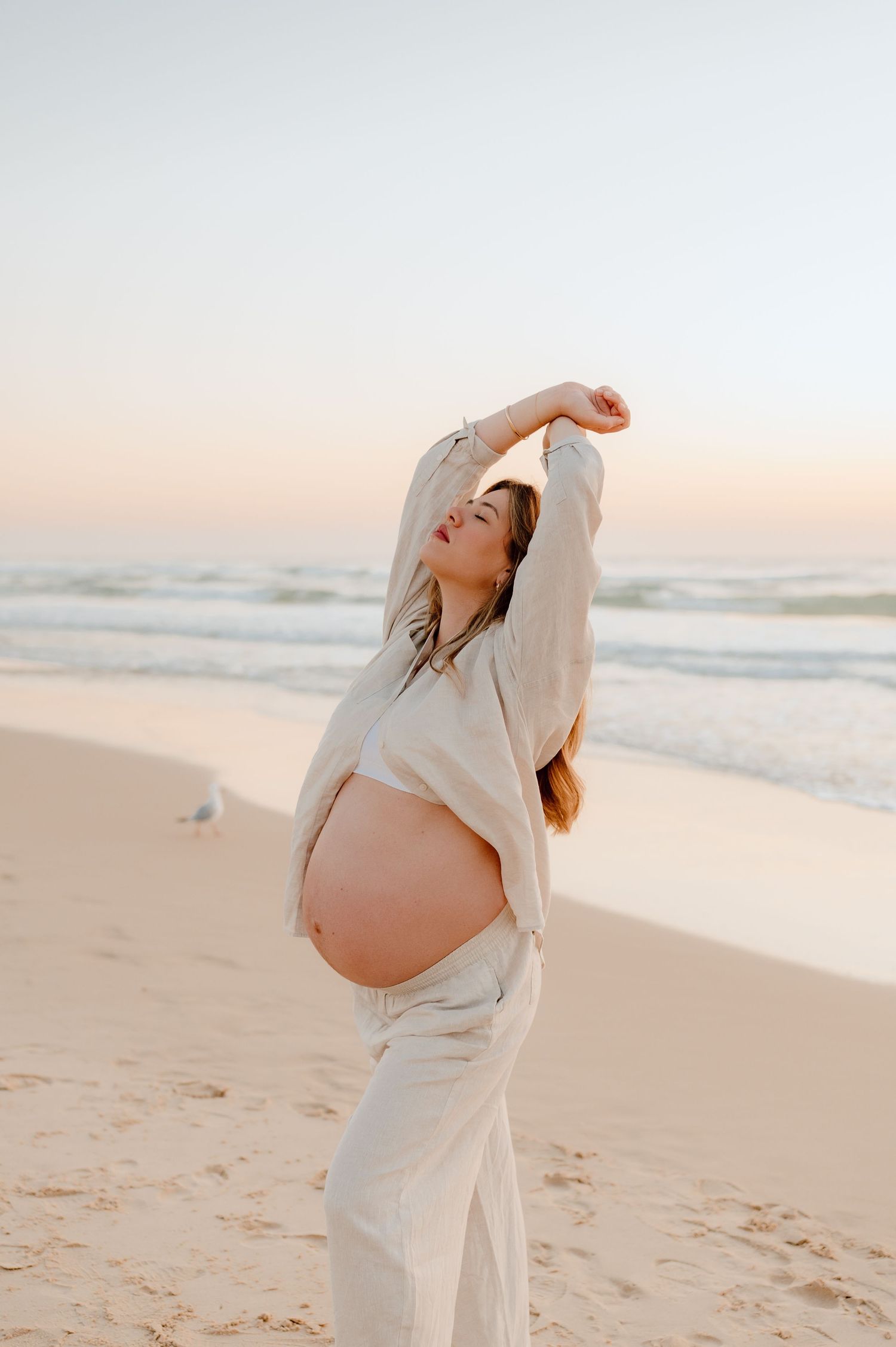 Artistic maternity portrait on beach at sunset showing pregnancy silhouette.