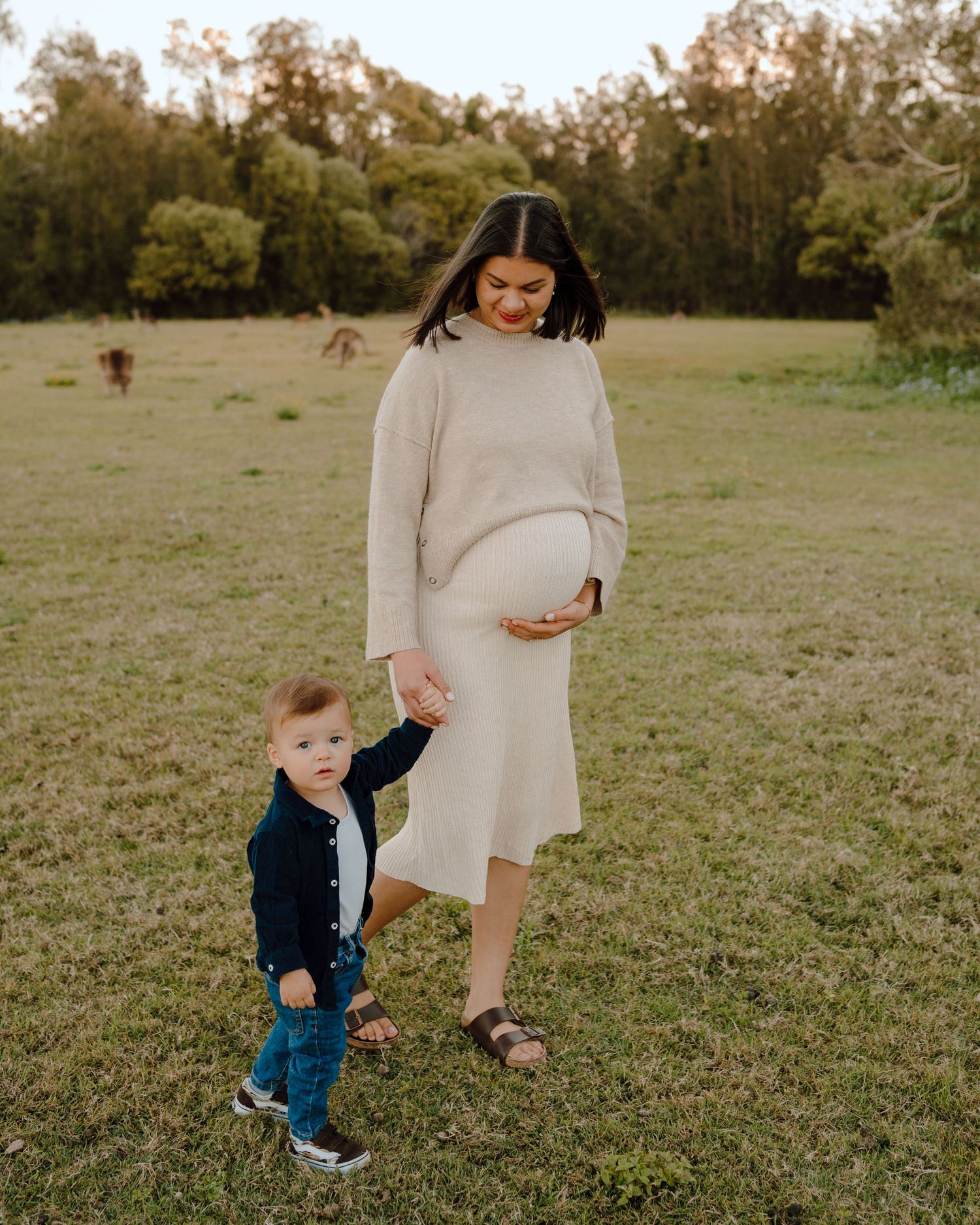 Family sharing playful moment in grassy field.