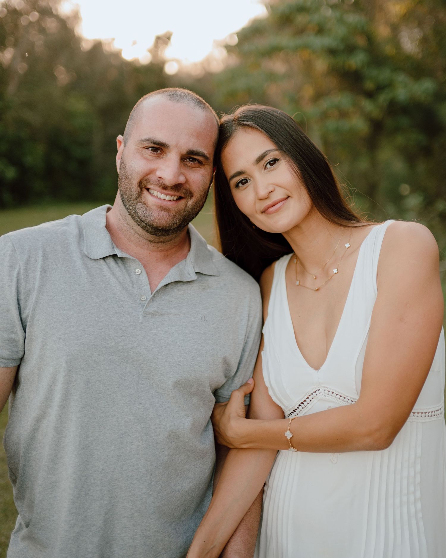 Couple in coordinated white and grey outfits sharing affectionate moments in a natural outdoor setting.