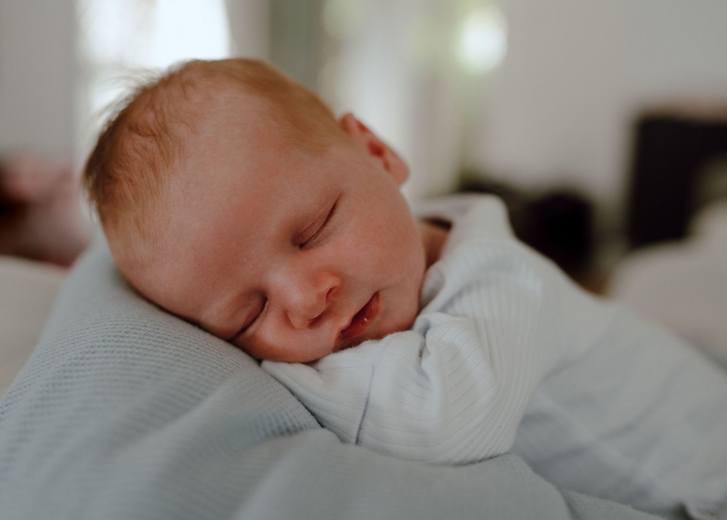 A peaceful newborn baby sleeping soundly on white bedding in a series of connected photographs.