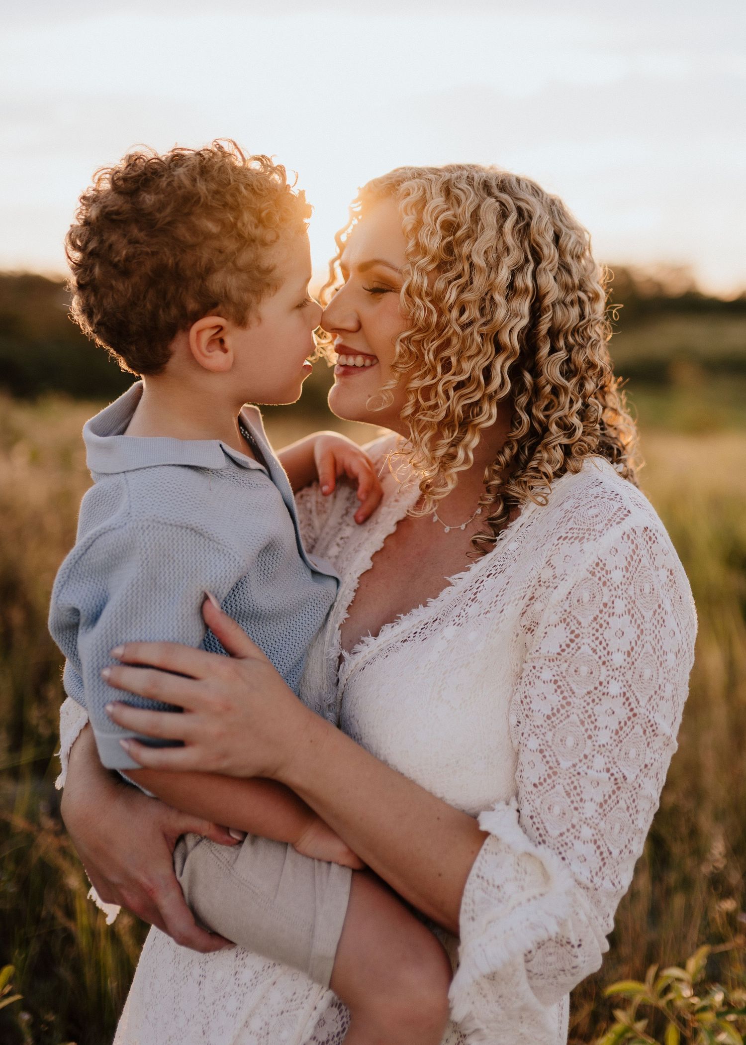 A tender moment between parent and child embracing in a sunlit field at golden hour.