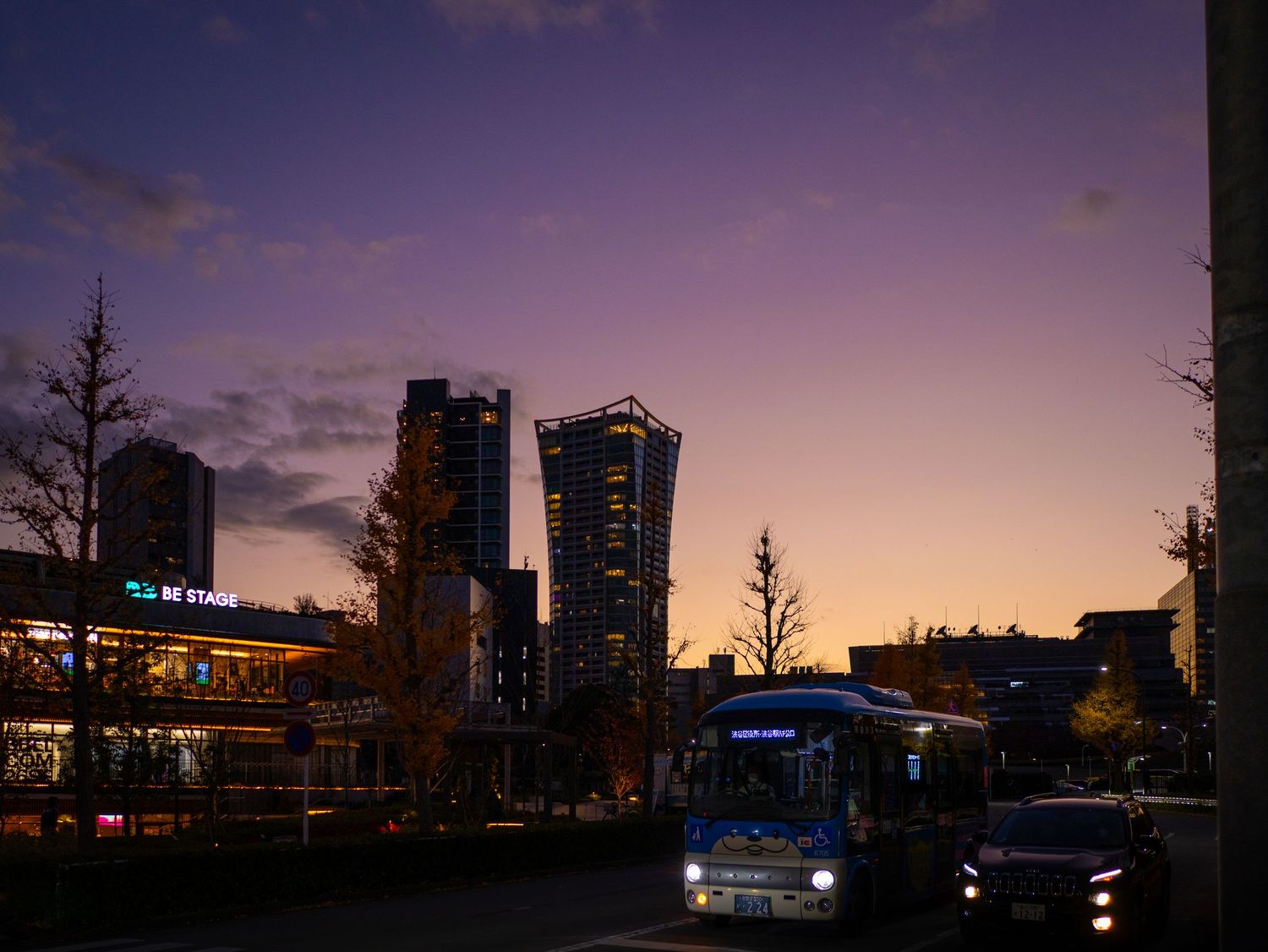 City skyline silhouetted against a purple sunset sky with illuminated buildings.