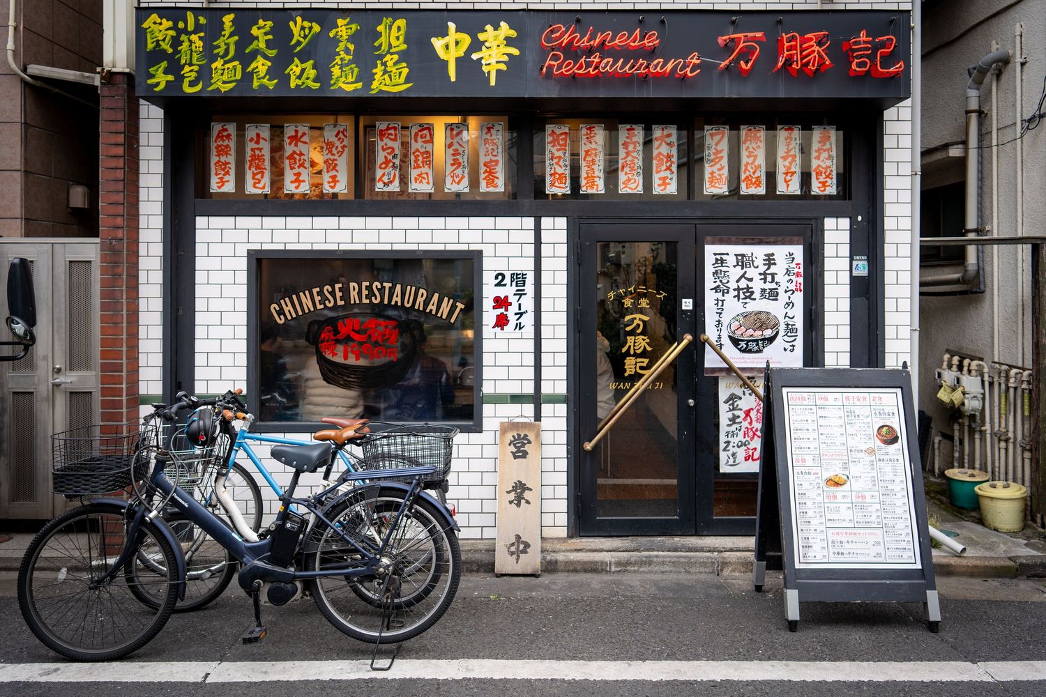 Row of traditional Japanese shop fronts with signs and banners displayed across storefronts.
