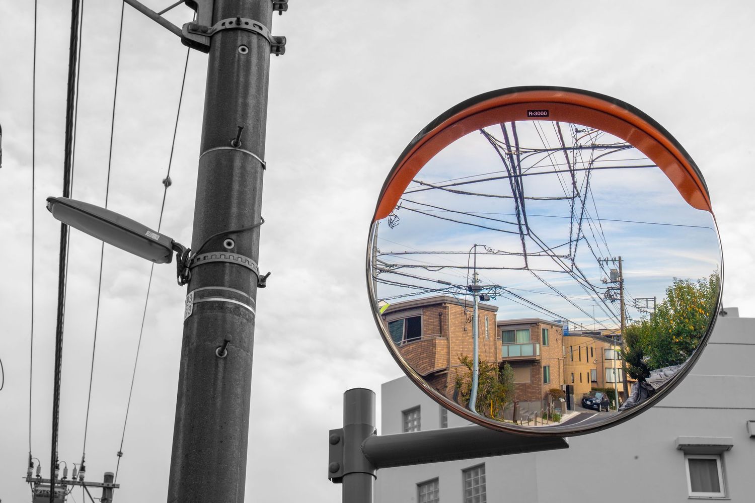 Series of convex traffic safety mirrors mounted on poles reflecting urban scenery.