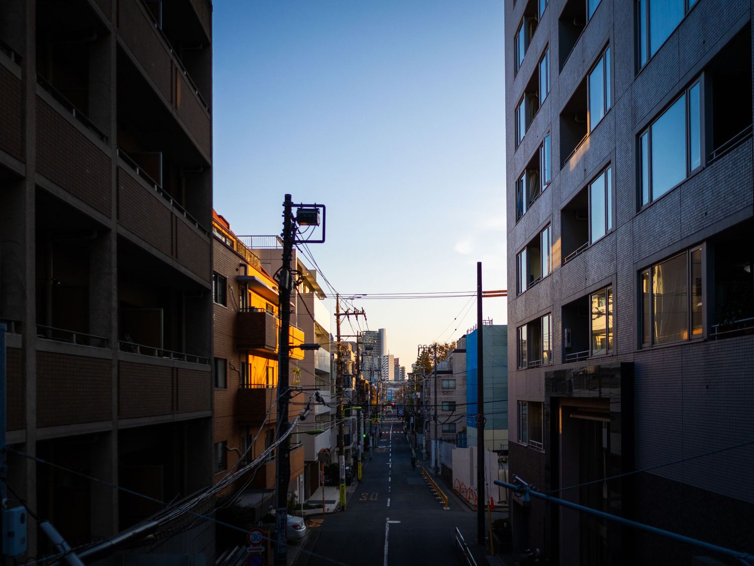 Row of modern apartment buildings along an empty street during blue hour.