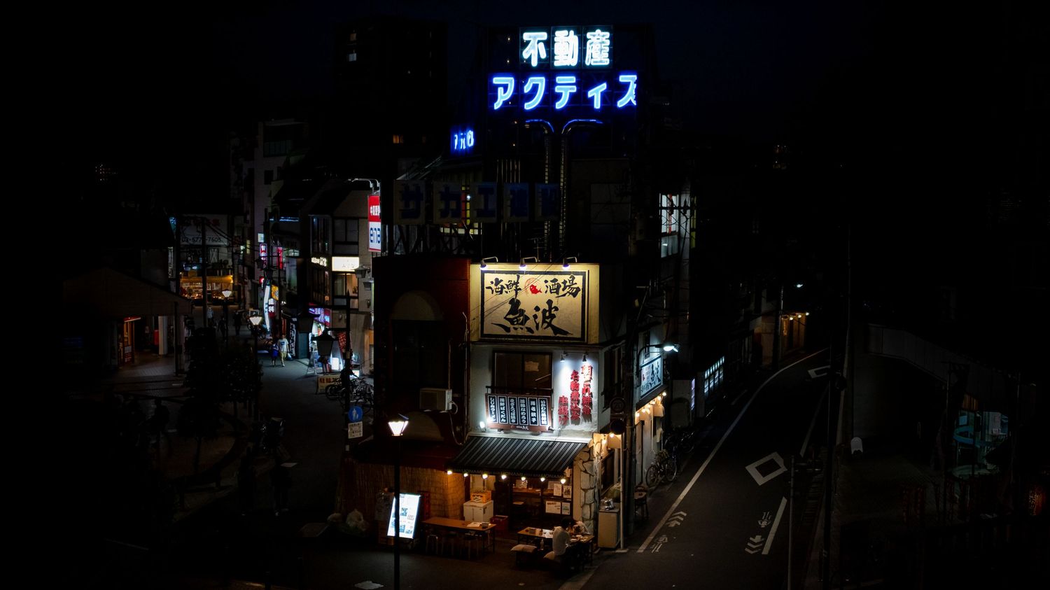 Japanese neon signs illuminating a dark urban street at night.