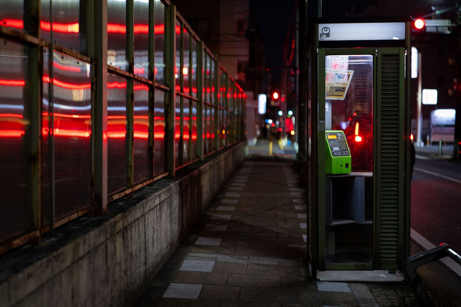 Dark subway platform illuminated by red neon lights creates an eerie atmosphere in an empty station corridor.