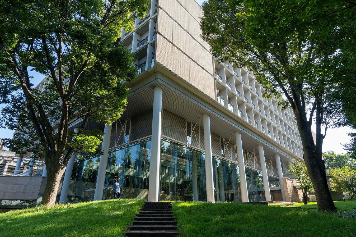Modern concrete building surrounded by mature trees and landscaping.