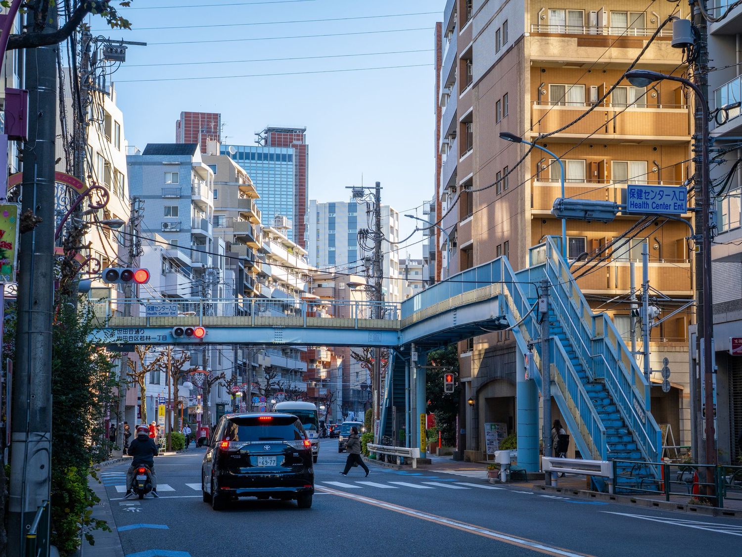 A narrow residential street in Japan with apartment buildings and power lines stretching between poles.