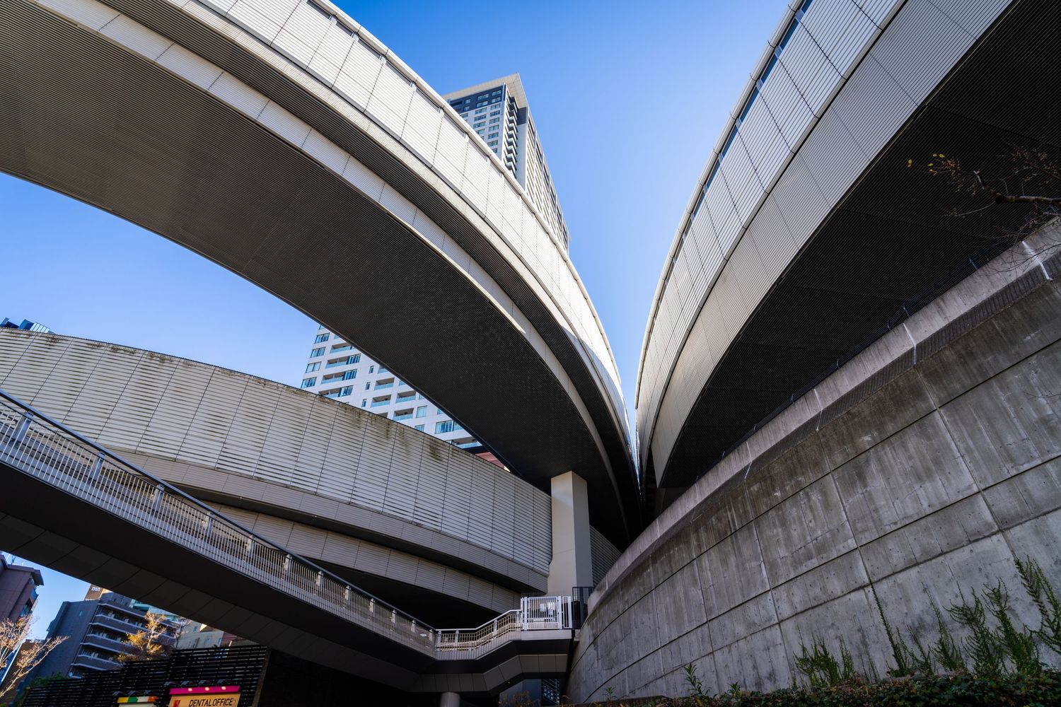 A series of elevated highway overpasses and concrete bridges intersecting against a bright sky background.