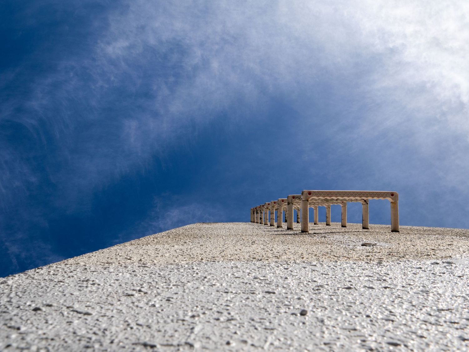 Ancient stone columns stand atop a snow-covered hill against a dramatic blue sky with wispy clouds.