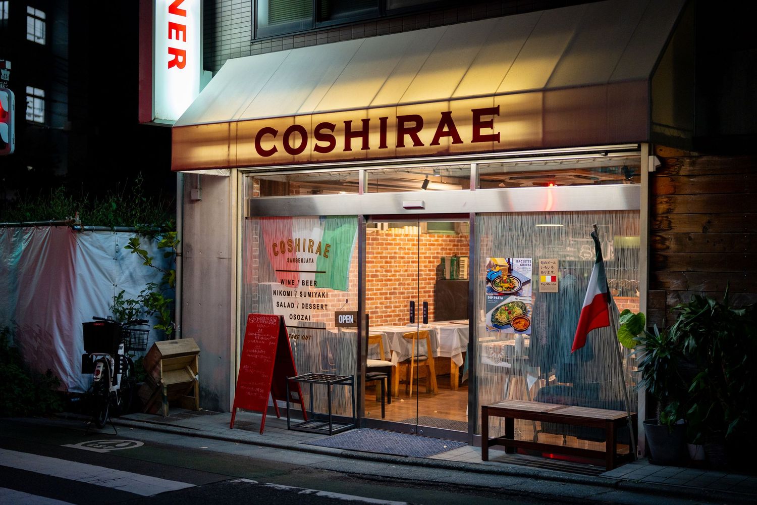 Illuminated storefront signs and displays at night in a Japanese shopping district.