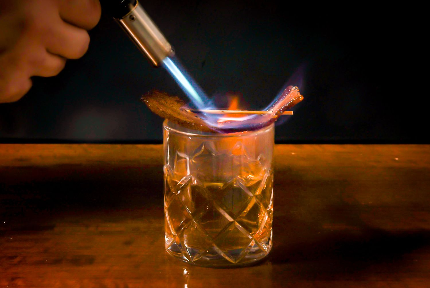 A photo of a cocktail being torched by a blowtorch.
