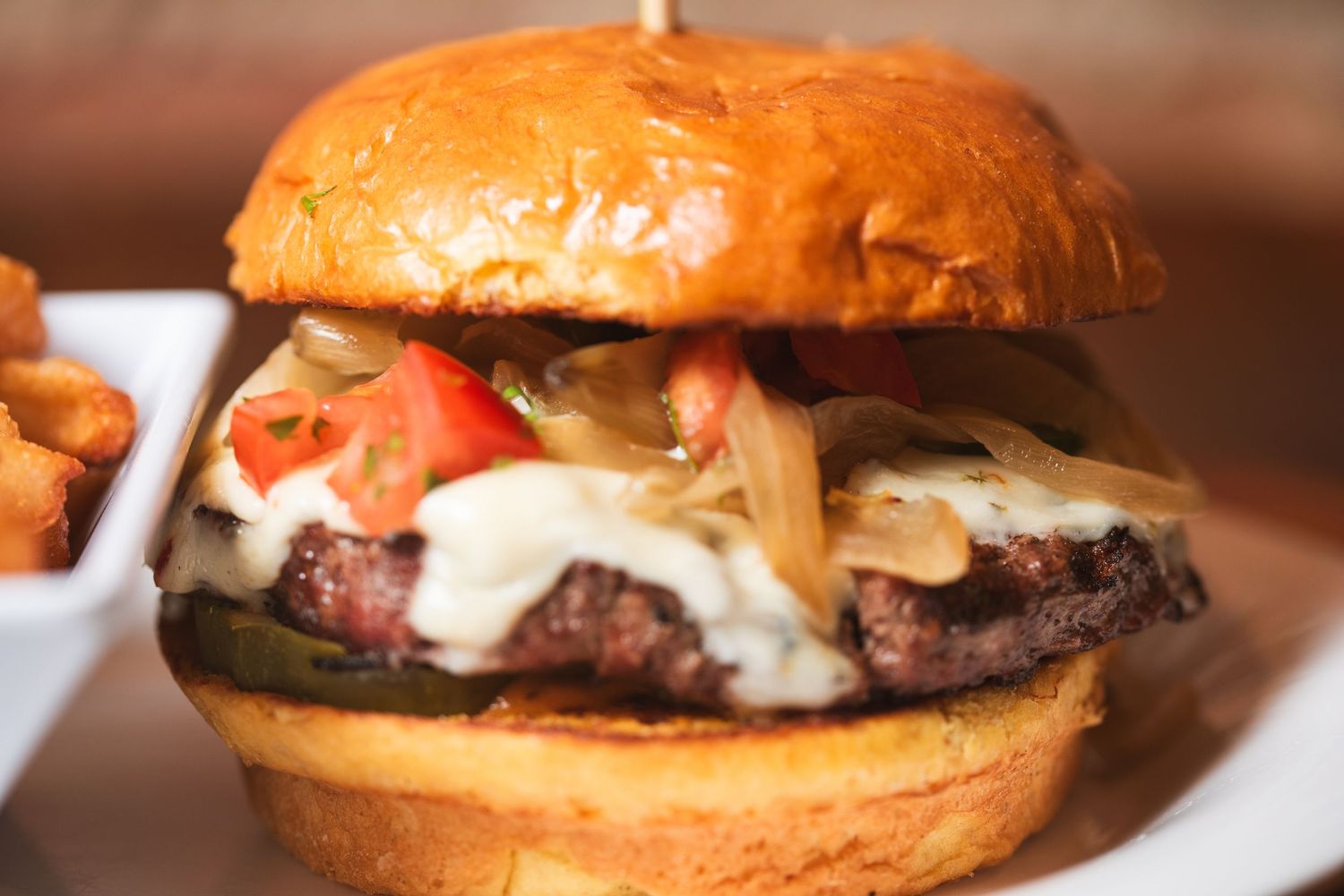 A gourmet cheeseburger with melted cheese, tomatoes, and lettuce served on a toasted brioche bun from Embers in Lockport, IL.