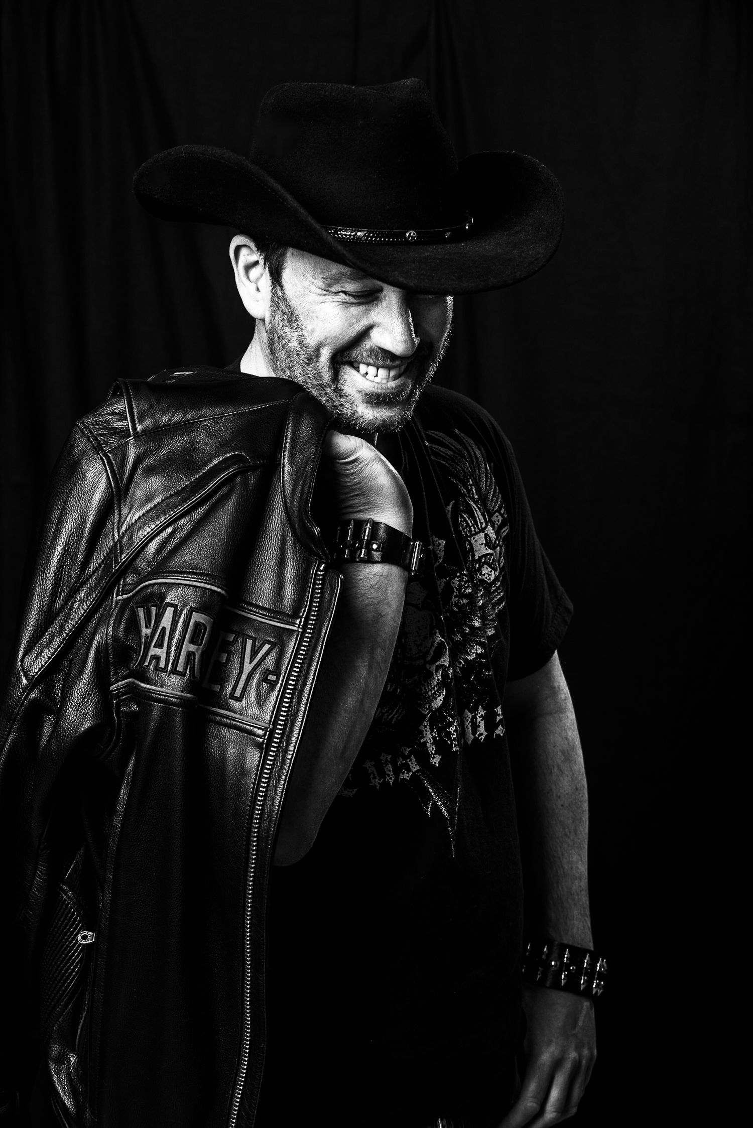 Dramatic black and white portraits featuring leather jacket and cowboy hat in low key lighting.
