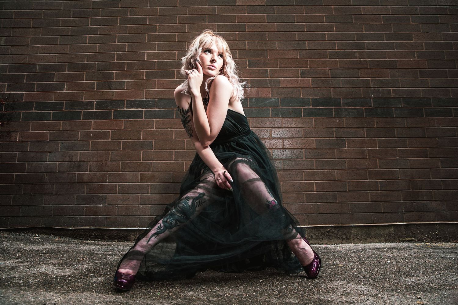 Artistic portrait series against brick wall with dramatic poses and lighting.