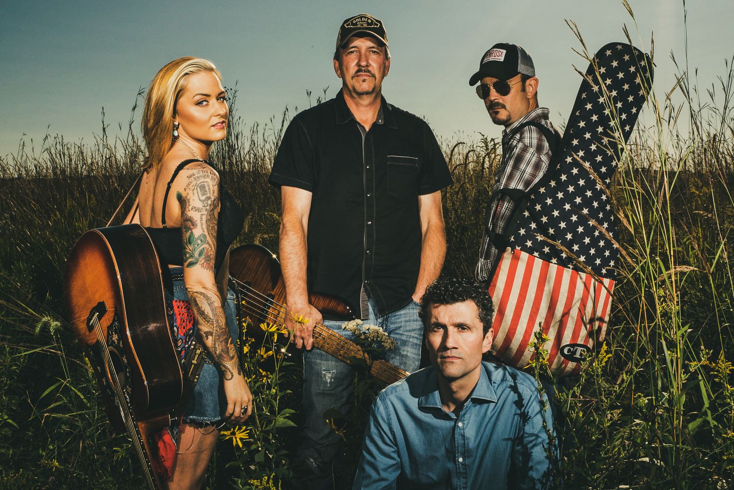 Group photo shoot in tall grass with American flag and rustic styling.