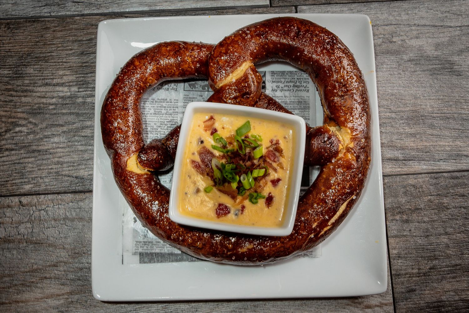 Gourmet pretzel with cheese dip served on white plate.