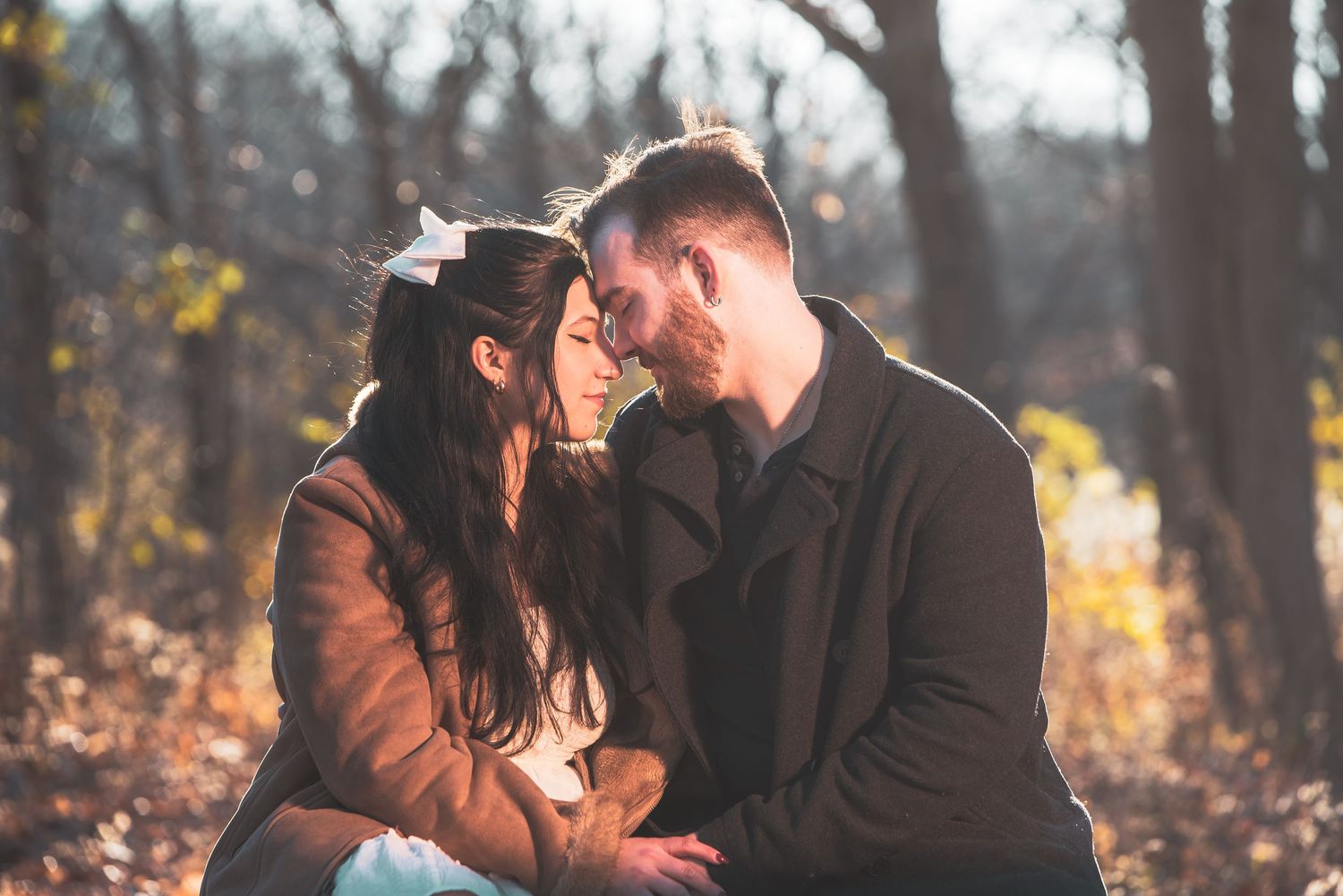 Romantic autumn engagement photos showing intimate moments between a couple in a wooded setting.