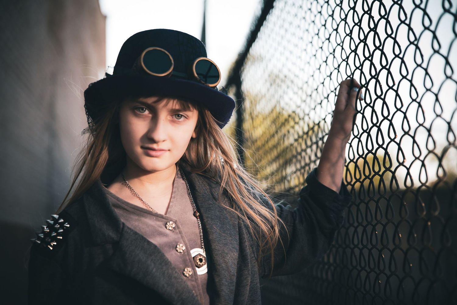 Dramatic  Steampunk portrait series against a chain link fence with moody lighting and shadows.