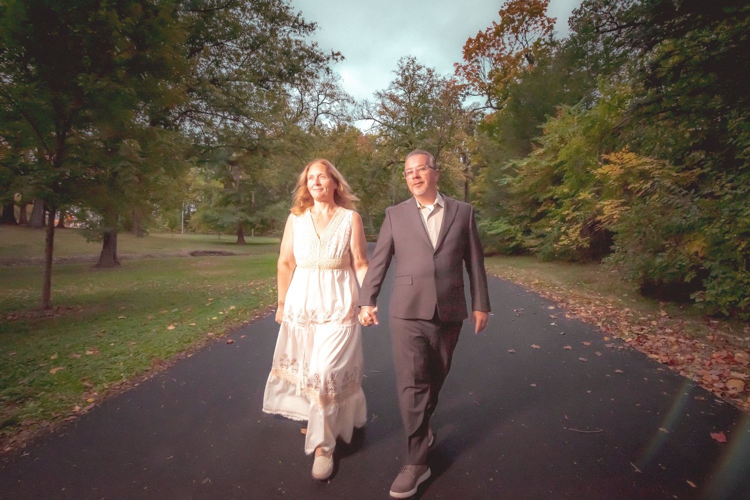 Bride and Groom walking along tree-lined path during fall season in New Lenox IL.