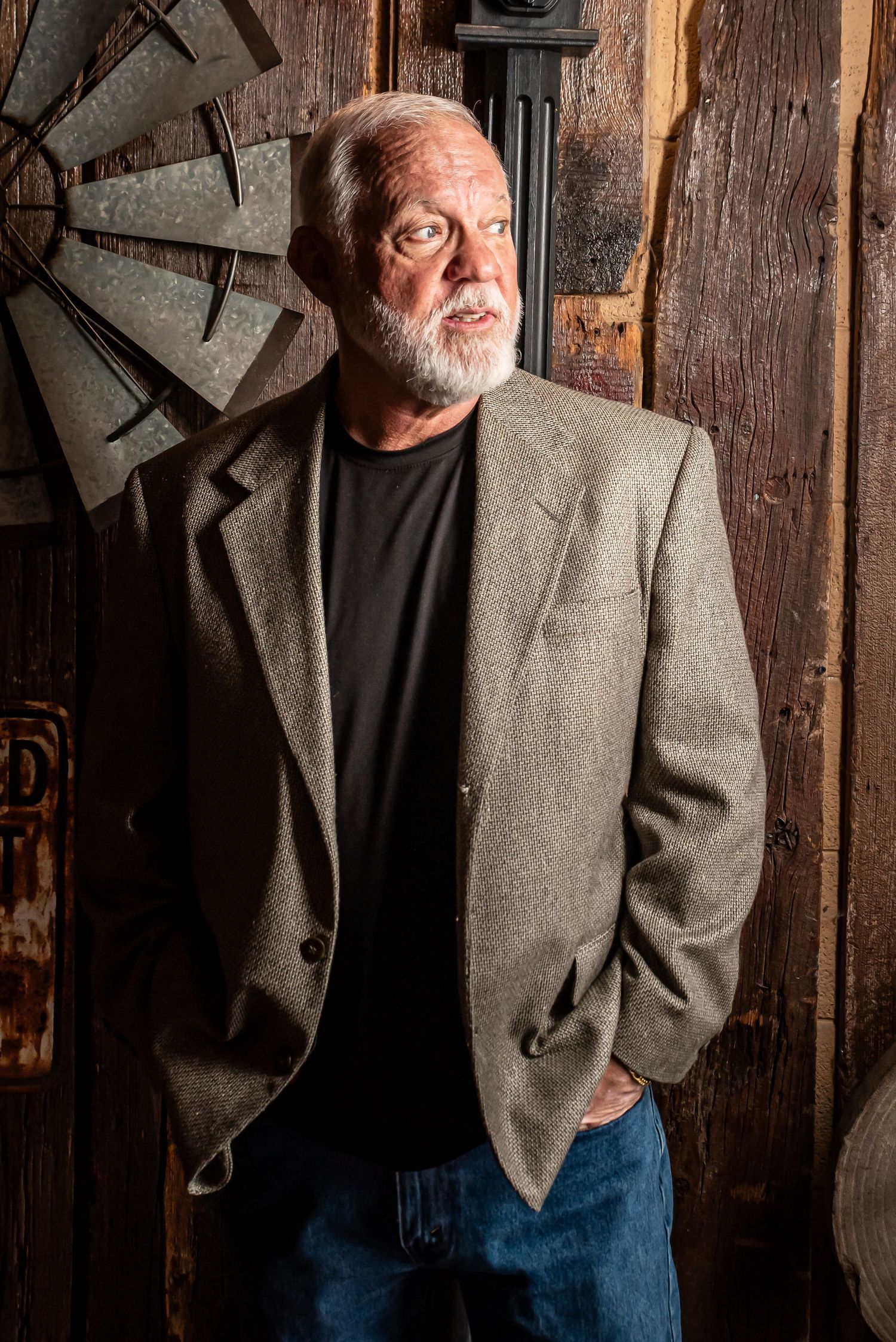 Portrait of mature man in blazer against rustic wooden wall with vintage decor.