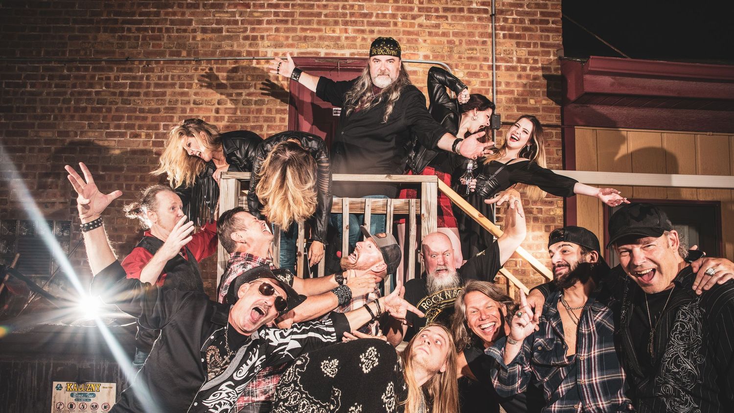 Energetic crowd celebrating at a party venue with brick walls and bright lighting.