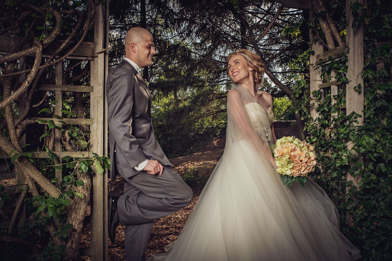 Wedding couple poses in a lush garden setting with natural greenery and romantic lighting.