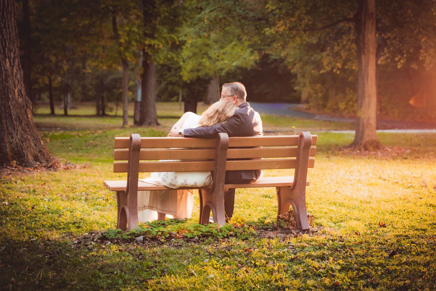 Park bench scenes in autumn with a bride and groom enjoying golden sunlight filtering through trees in New Lenox, IL.