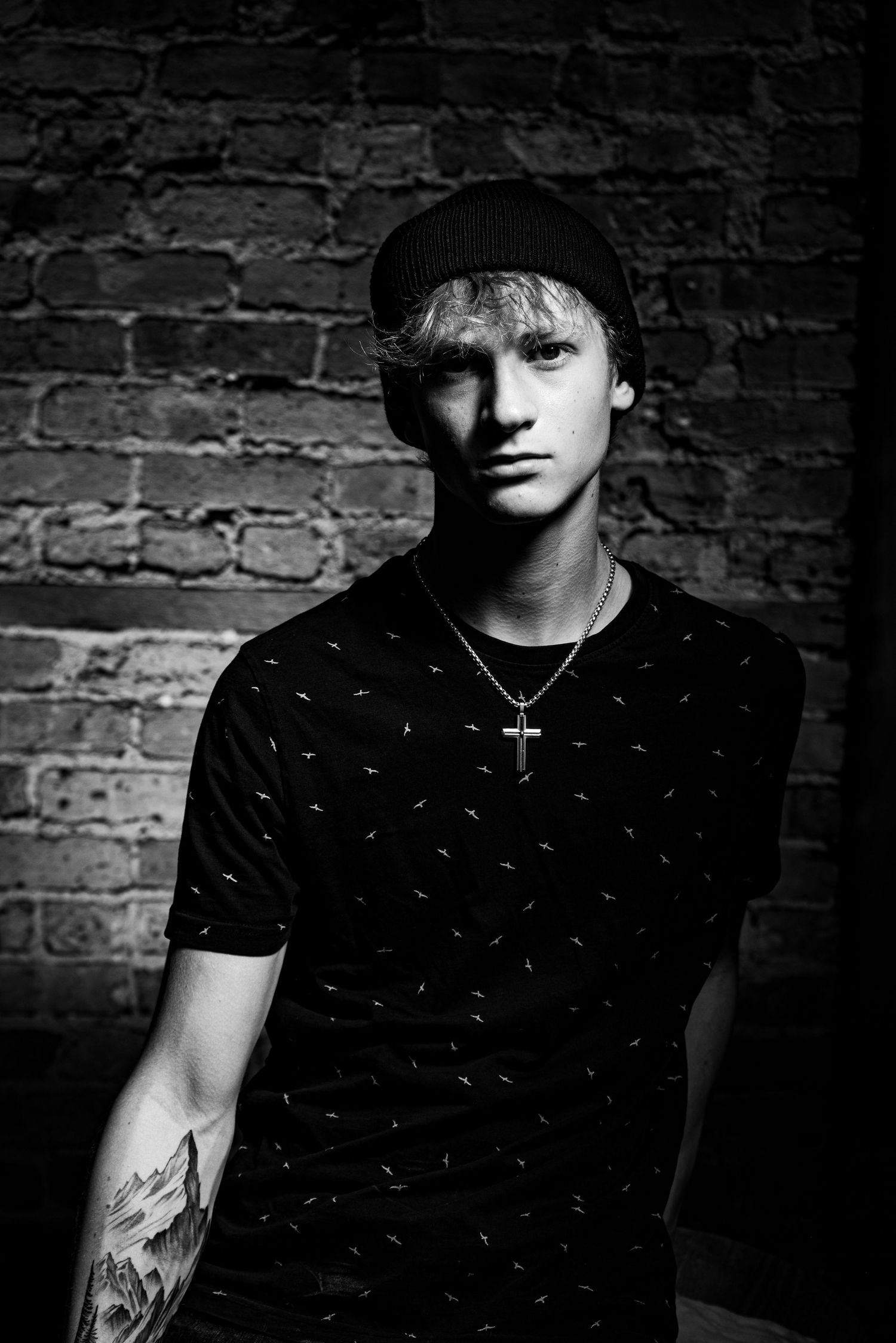 Moody black and white senior portrait against brick wall with dramatic shadows shot in Lockport, IL