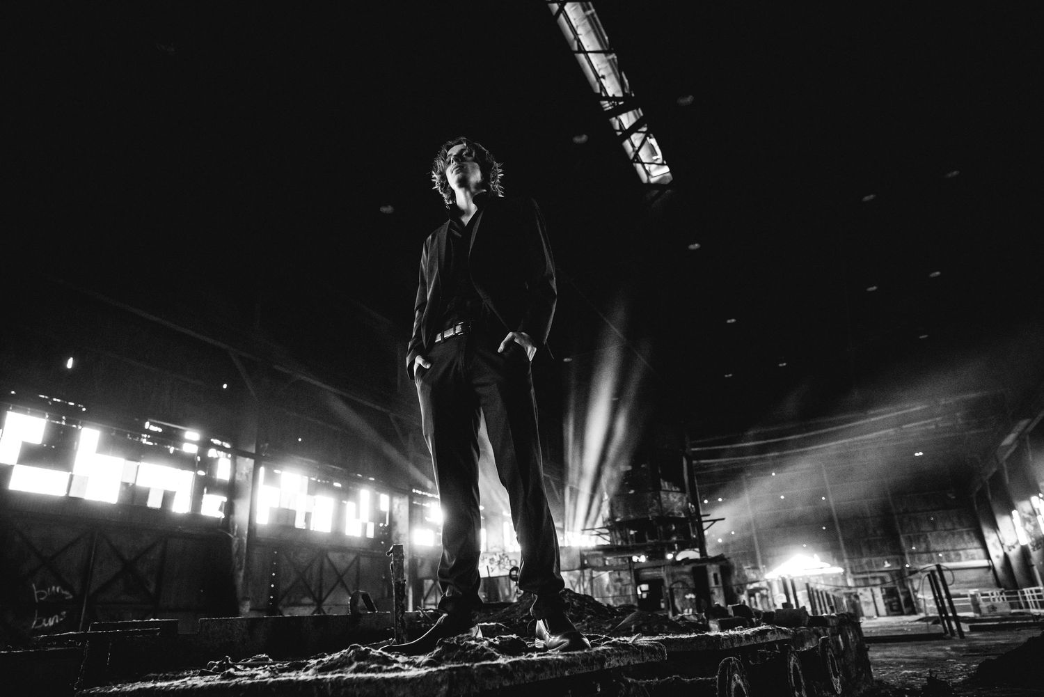 Dramatic black and white concert photo showing silhouette on stage with bright lights.