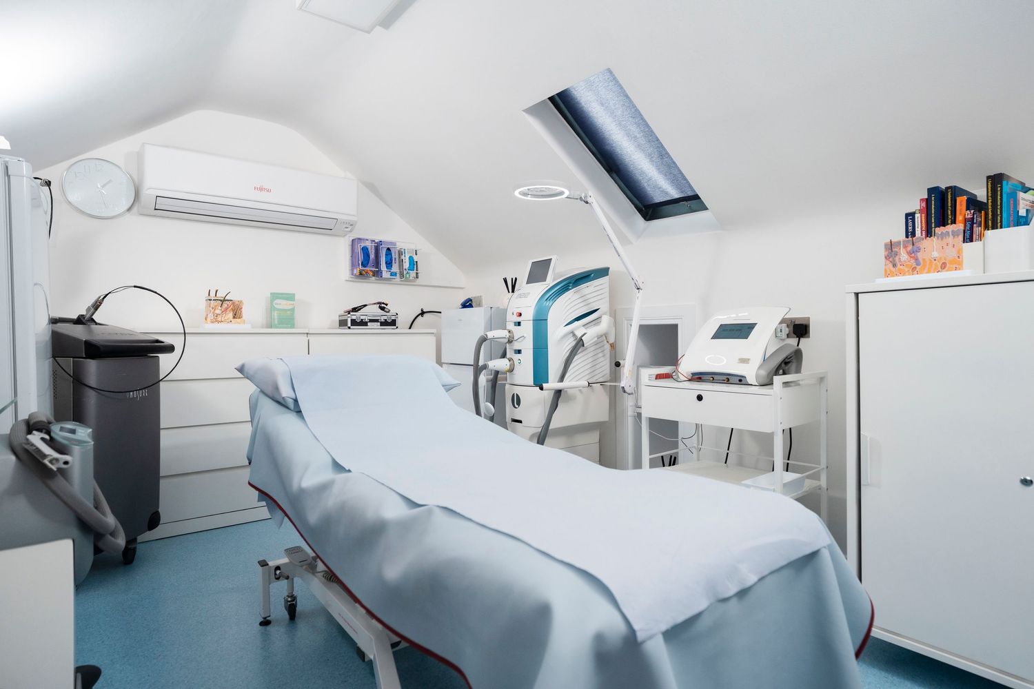 Modern medical treatment room with blue examination table, laser equipment and skylight ceiling. Jenny Flanagan