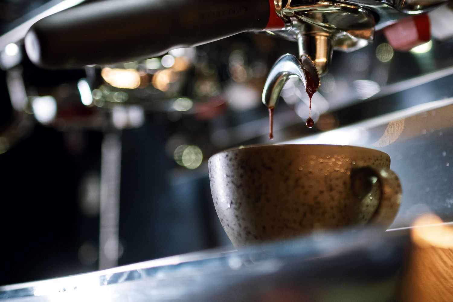 Espresso shot dripping into a rustic ceramic cup on a professional coffee machine. Bailies Coffee Roasters