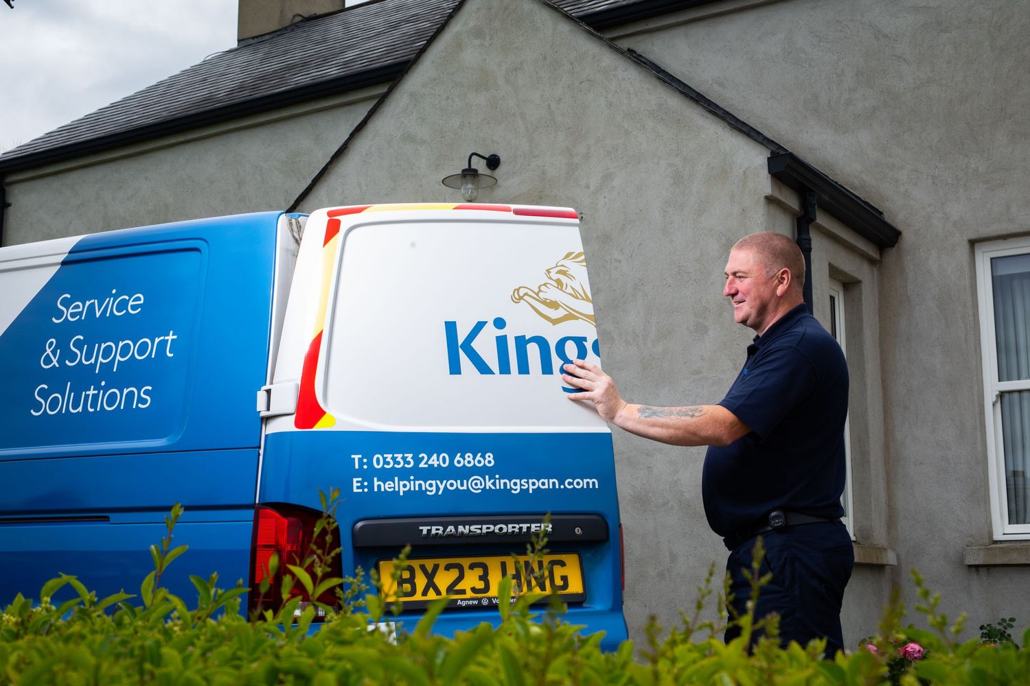 Kingspan service engineer standing beside branded blue service van outside residential property. Kingspan Water & Energy