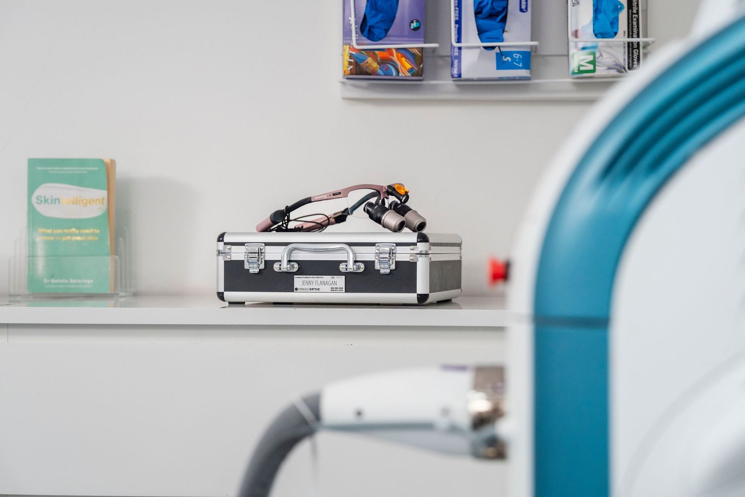Medical clinic shelf with supplies and equipment case beside blue laser treatment machine. Jenny Flanagan