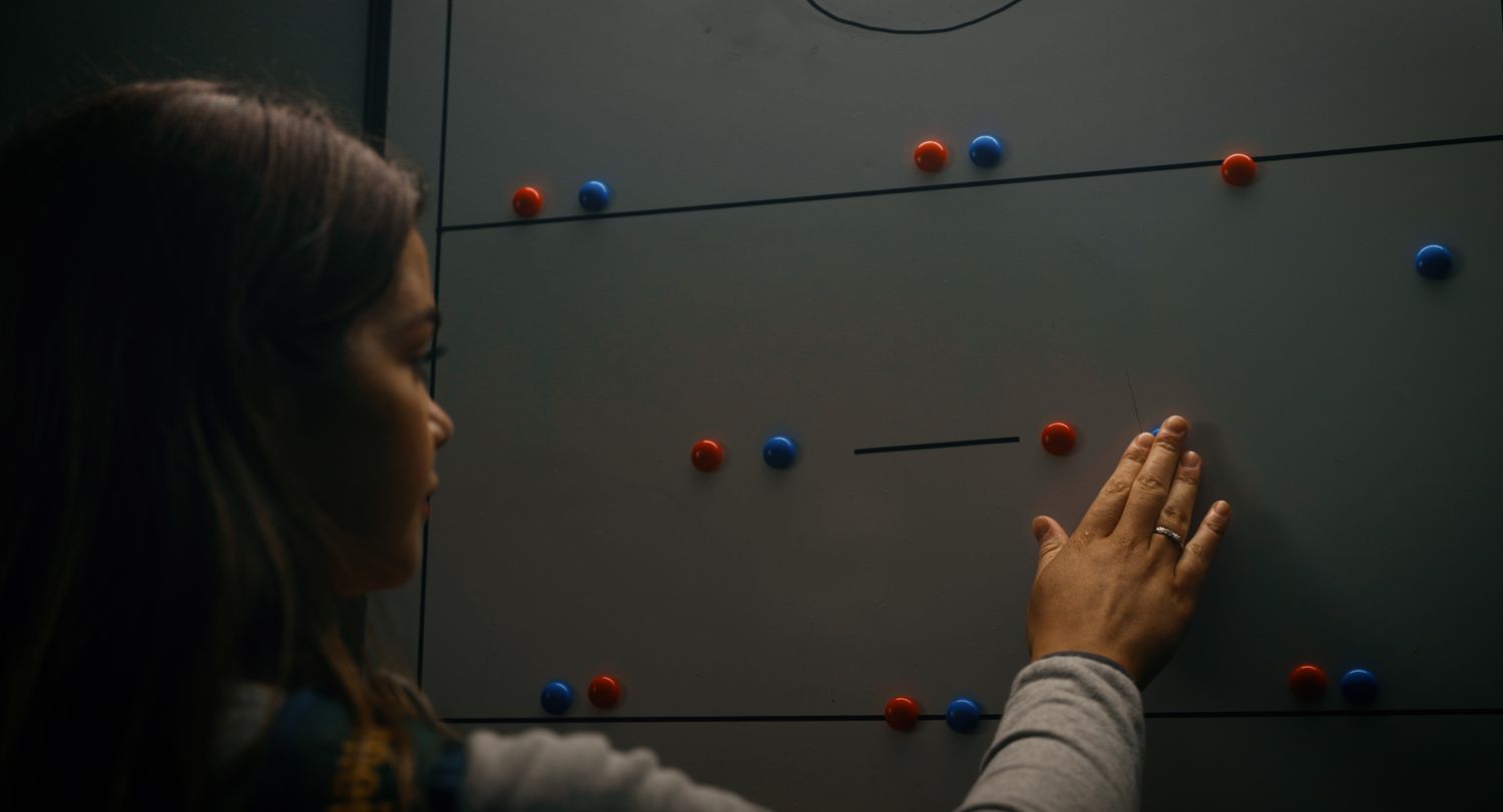 Woman arranges red and blue magnetic dots on a tactical sports board in a dark room. Ulster GAA