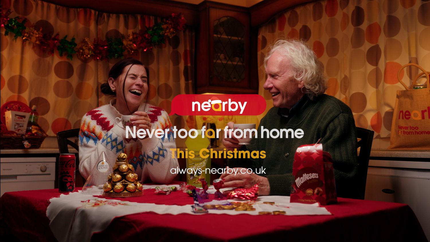 Two people share a joyful moment at festive table in Nearby Christmas advertisement campaign. Nearby Stores, S&W wholesale, TV Advert