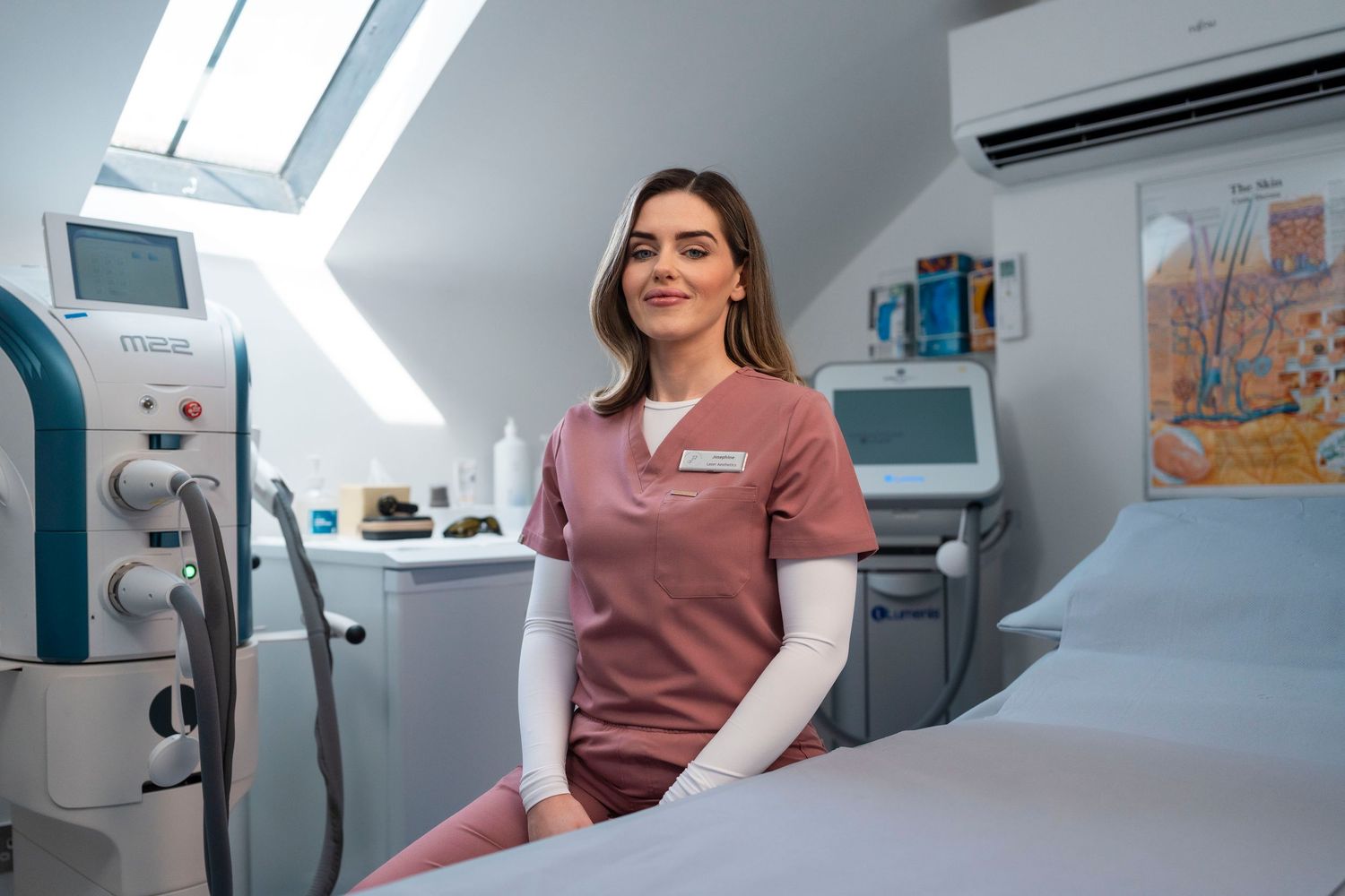 Female healthcare professional in pink scrubs sitting in a modern medical treatment room. Jenny Flanagan