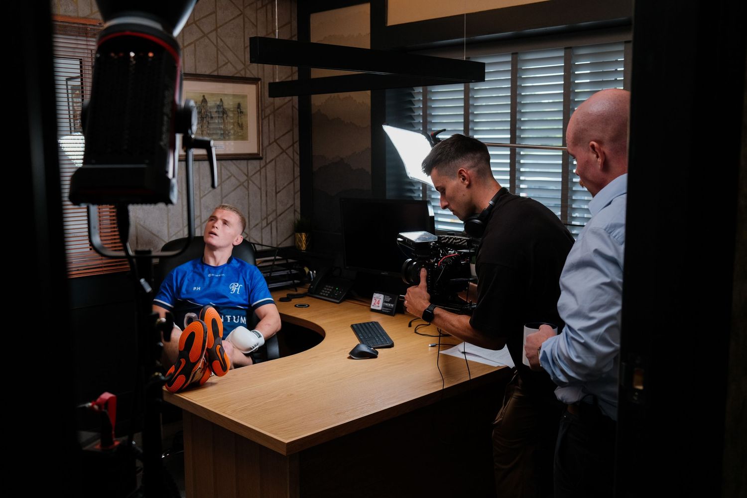 Film crew interviewing an elderly man at a desk in an office during a professional video production shoot. Centum Engineering