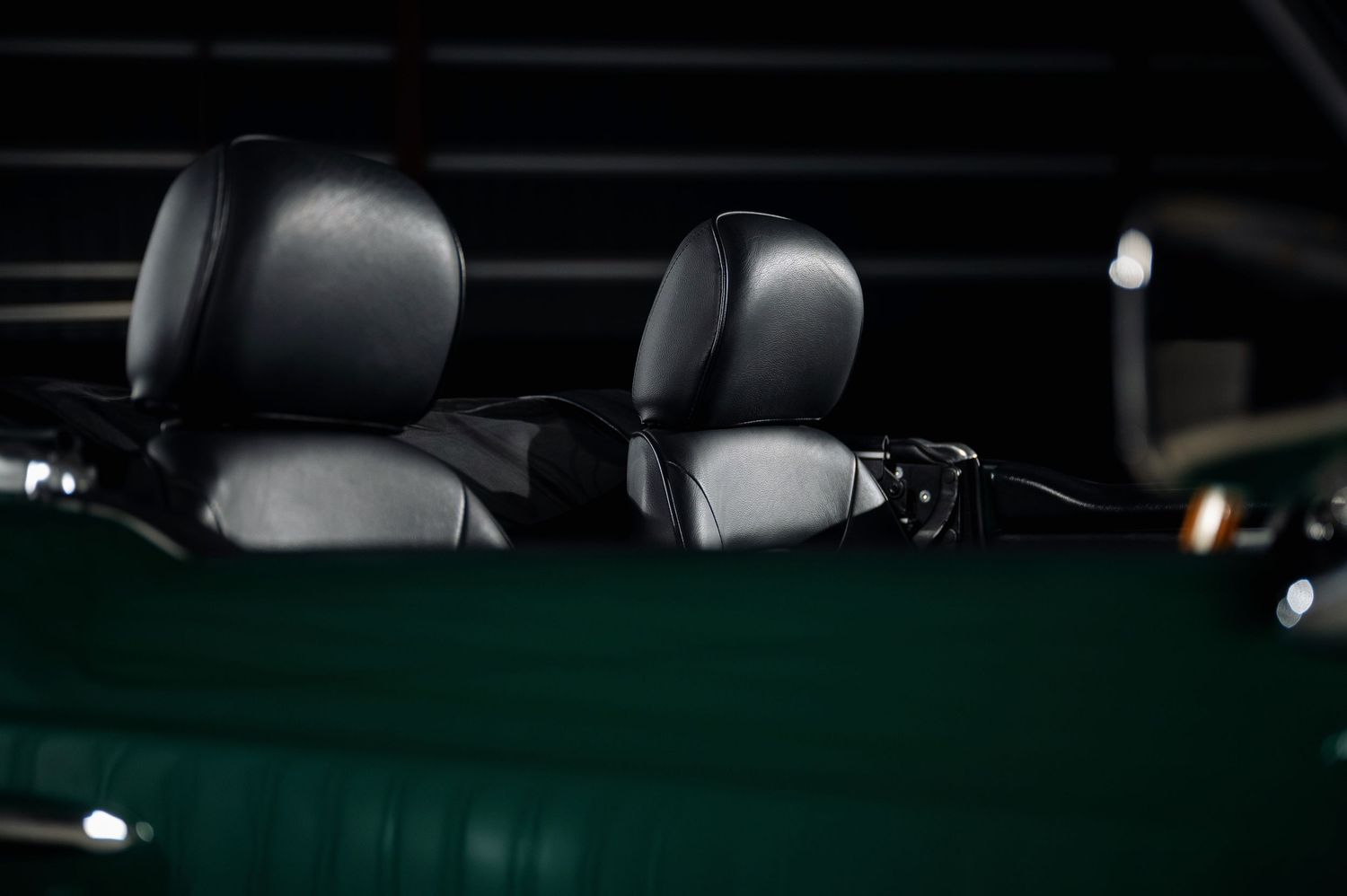Black leather bucket seats with headrests inside a British Racing Green Triumph TR6 classic convertible sports car. Motorist Collection
