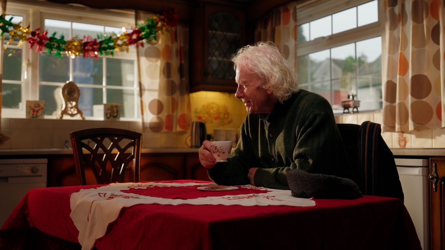 Elderly person sitting alone at a festively decorated red tablecloth dining table during Christmas. Nearby Stores, S&W wholesale, TV Advert