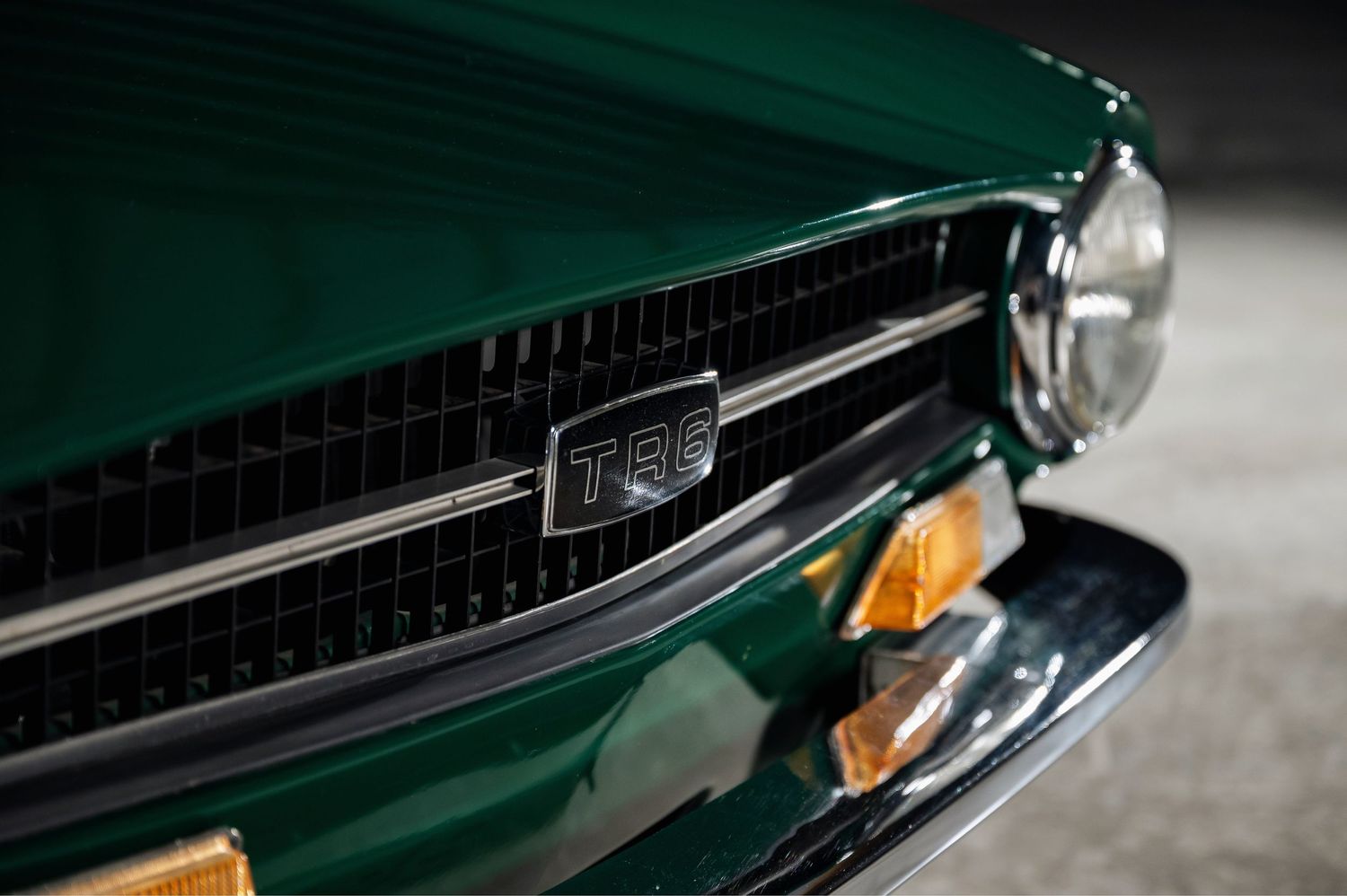 Front grille close-up of a British Racing Green Triumph TR6 classic sports car with chrome TR6 badge. The Motorist Collection