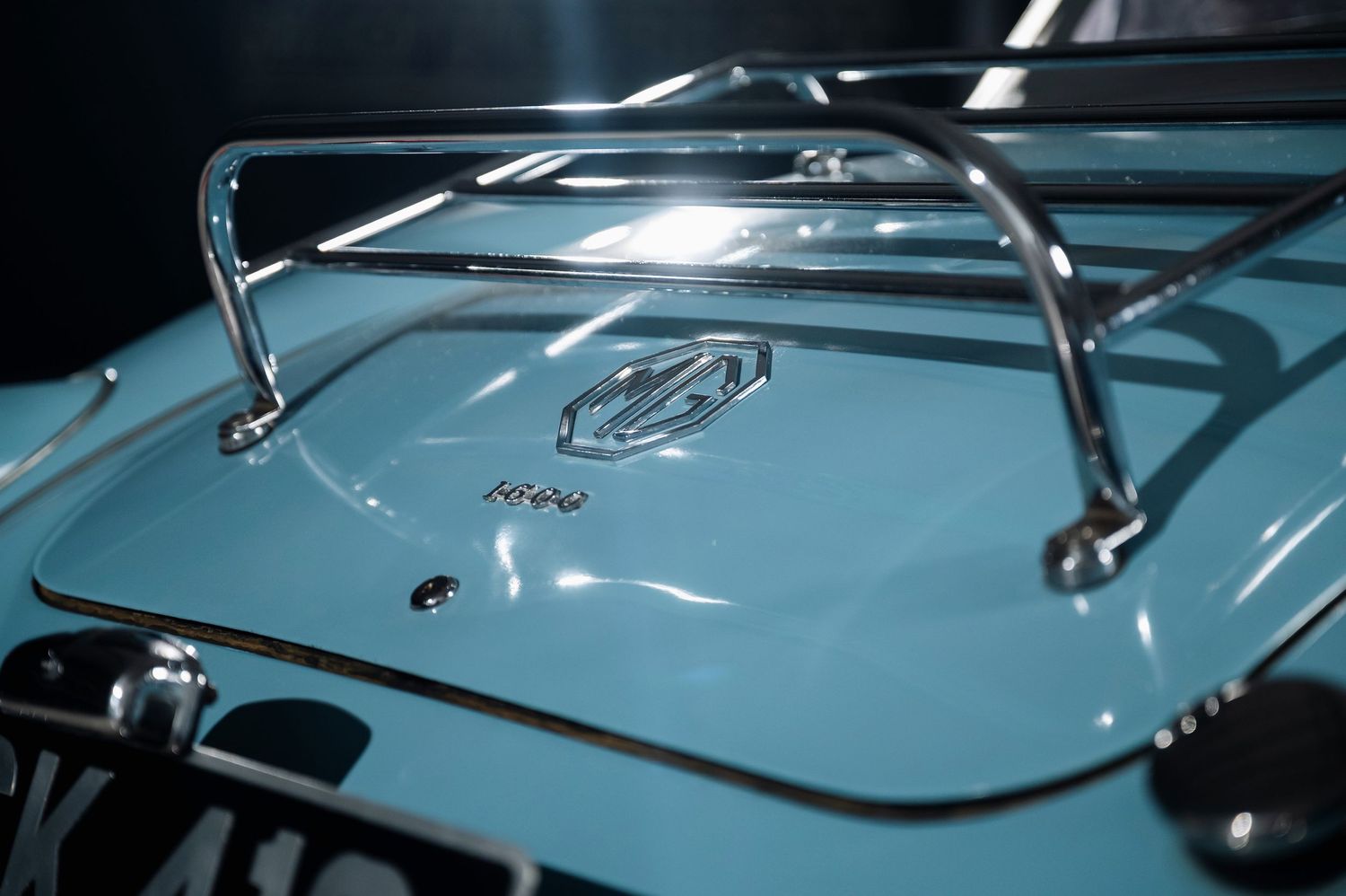 Chrome luggage rack and MG emblem detail on the trunk lid of a light blue classic MGA sports car. Motorist Collection