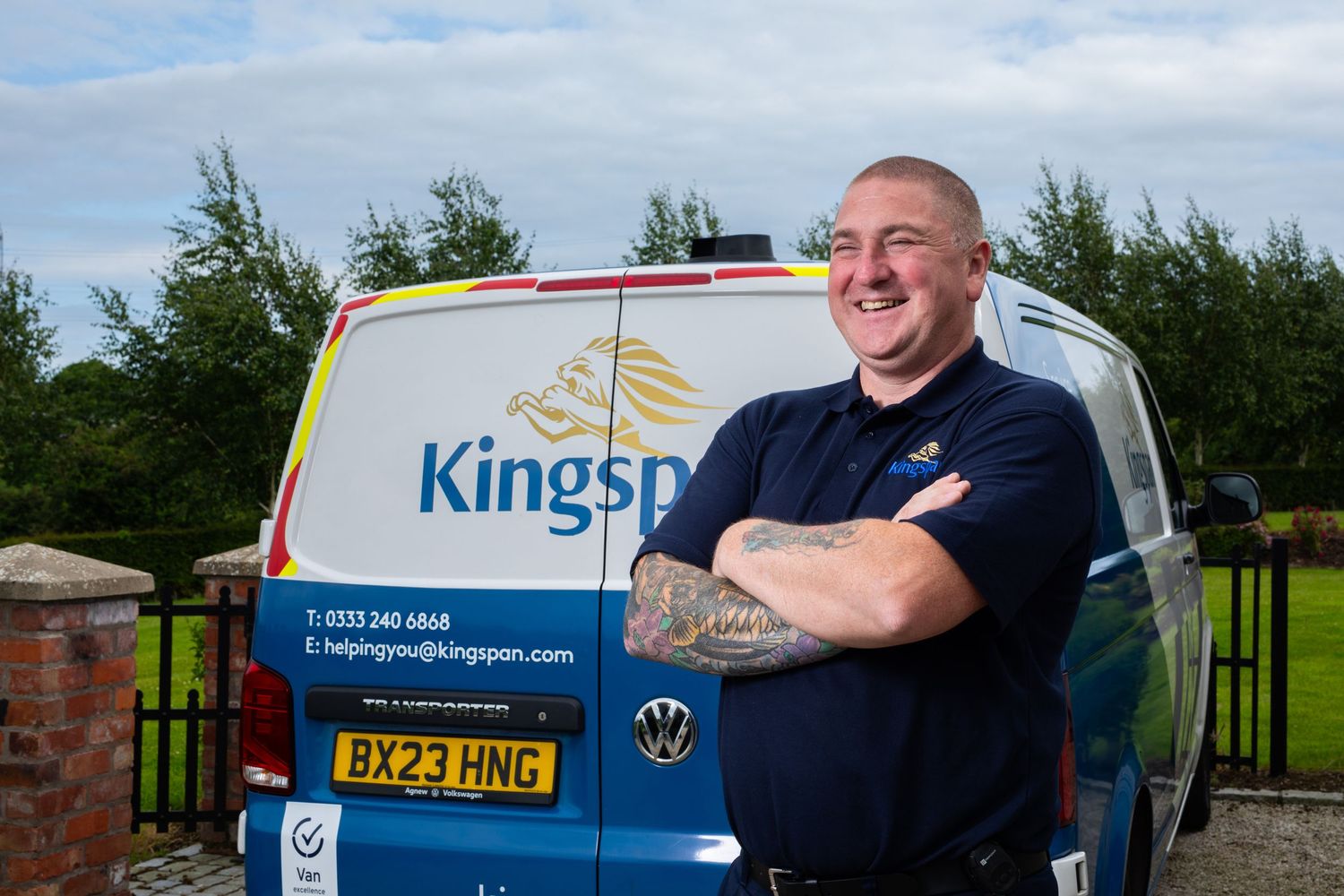 Kingspan service engineer in uniform standing confidently in front of a branded blue company van. Kingspan Water & Energy