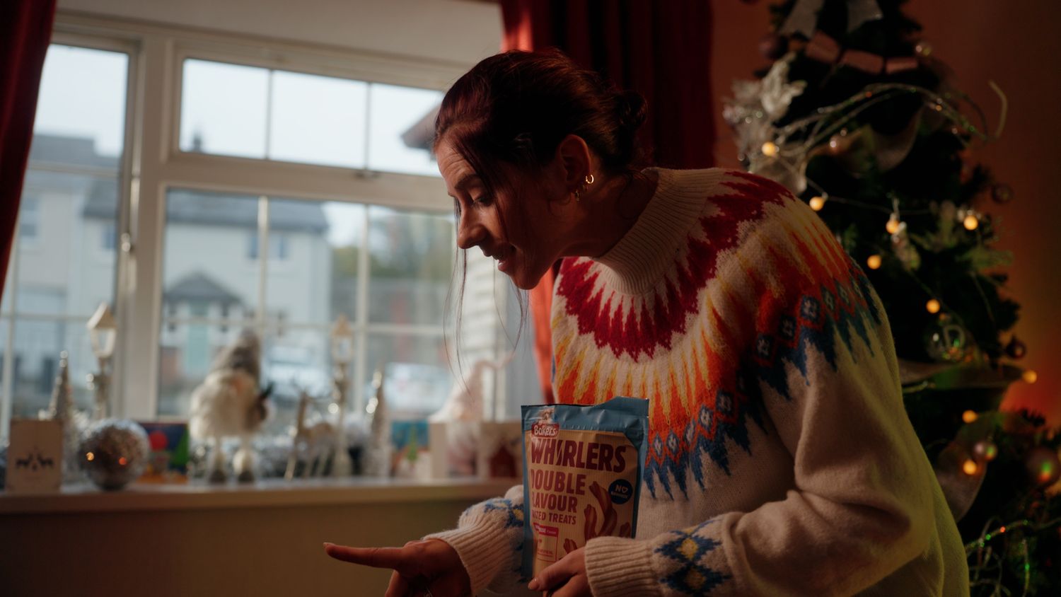 Person in colorful sweater holding a Wrigley's gum box near a decorated Christmas tree indoors. Nearby Stores, S&W wholesale, TV Advert