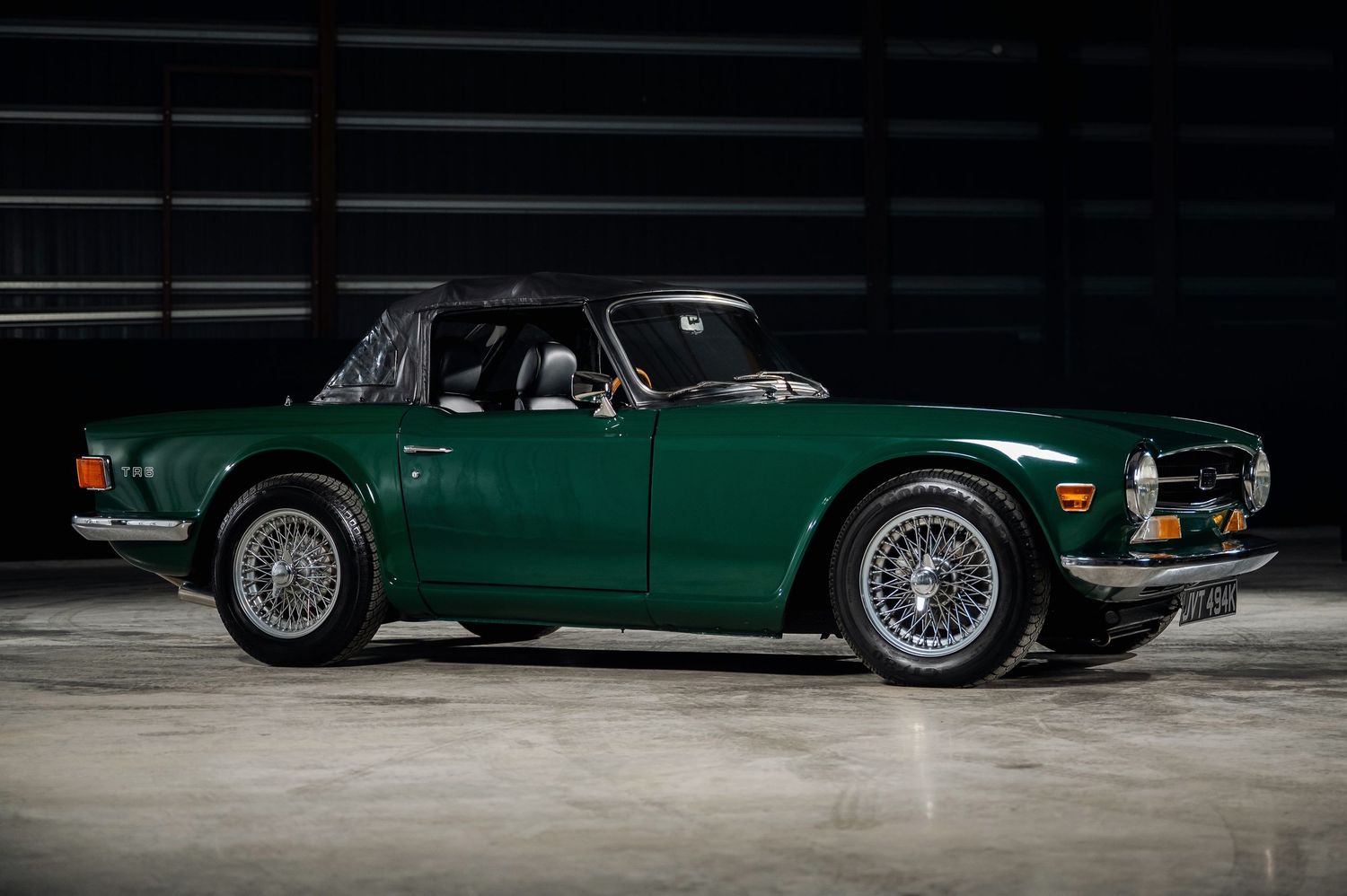 British Racing Green Triumph TR6 classic convertible sports car parked indoors with alloy wheels and black soft top. Motorist Collection