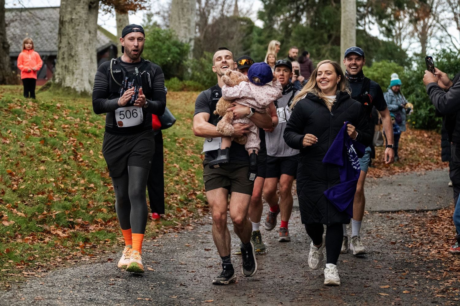 Group of runners participating in an outdoor charity fun run on a wet autumn day in a park.