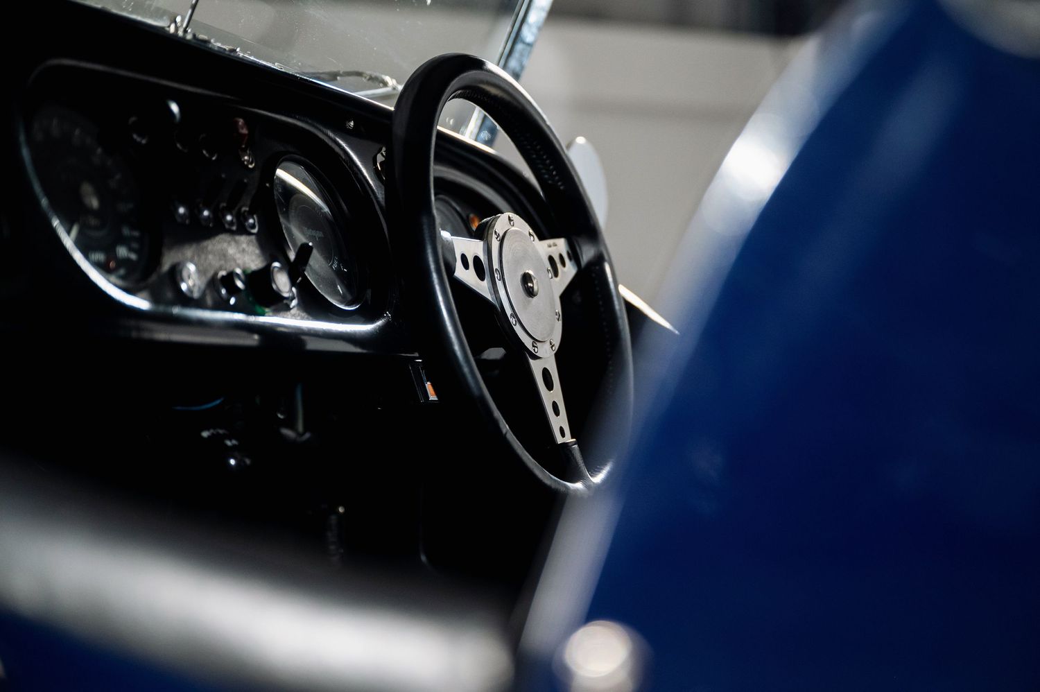 Vintage three-spoke steering wheel and instrument cluster detail of a classic British sports car interior. Motorist Collection